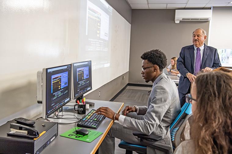 A student uses the new Bloomberg Terminal during class as Professor Richard Bookbinder looks on.